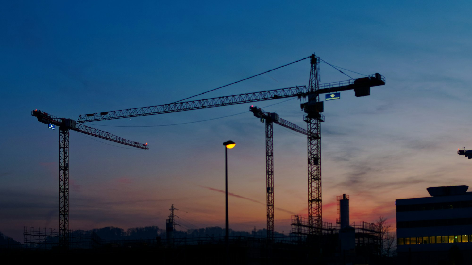 Gruas de construção contra o céu do fim de tarde